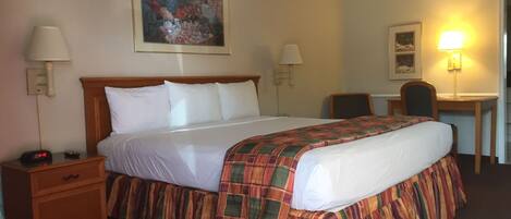 A hotel room with a bed, bedside tables, a desk, and a chair.