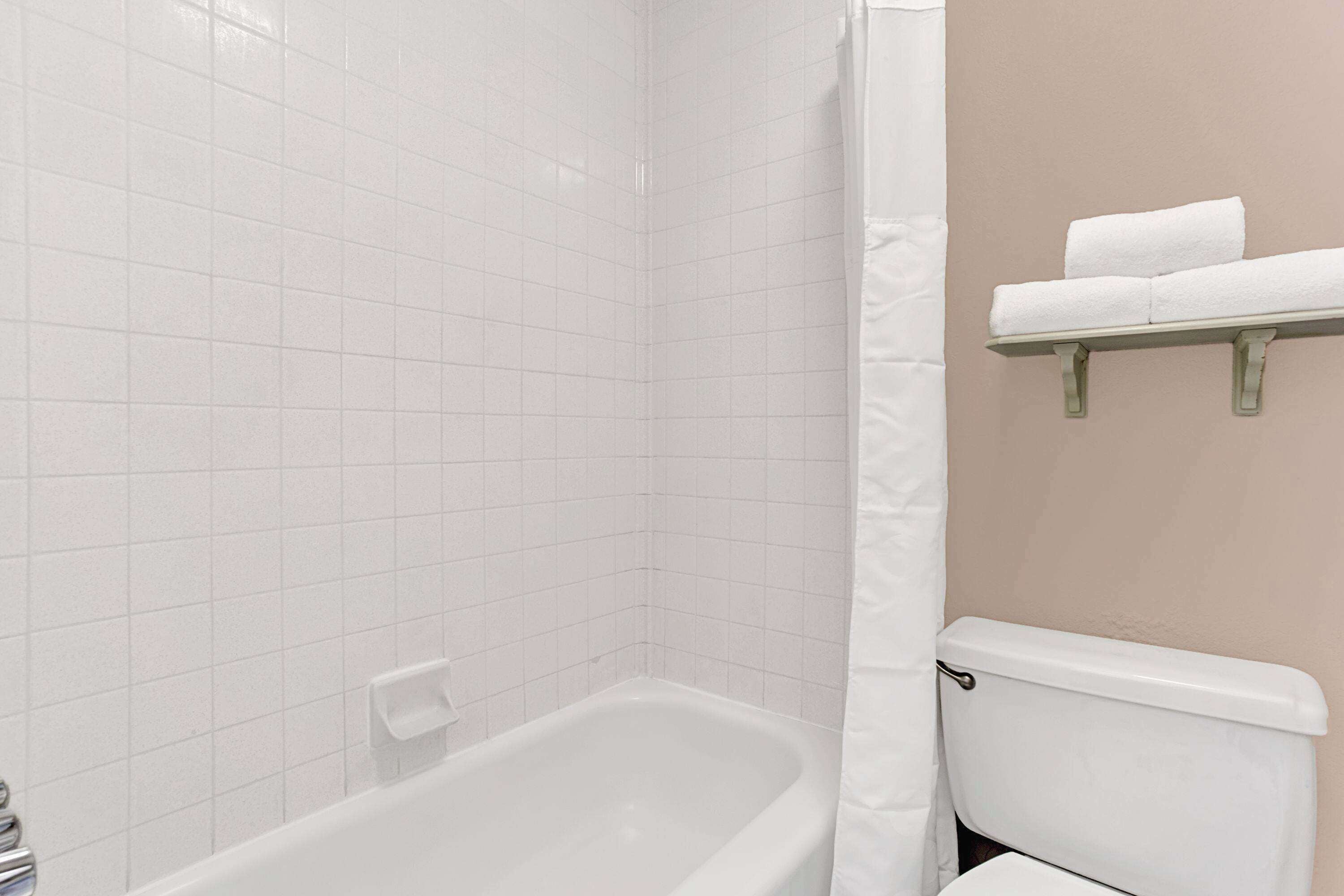 A bathroom with a white bathtub, a toilet, and a towel rack.