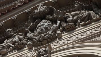 Eine detaillierte architektonische Skulptur mit aufwendigen Schnitzereien und einer liegenden Figur.