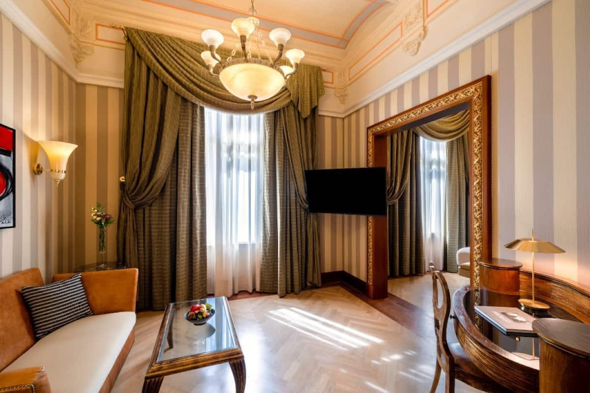Une chambre d’hôtel avec un canapé, une table basse, une télévision et un grand miroir.
