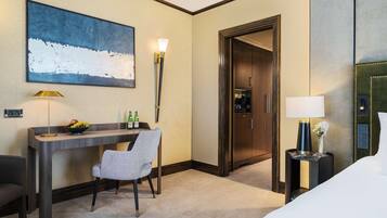 A hotel room with a desk, chair, bed, and a large abstract painting on the wall.