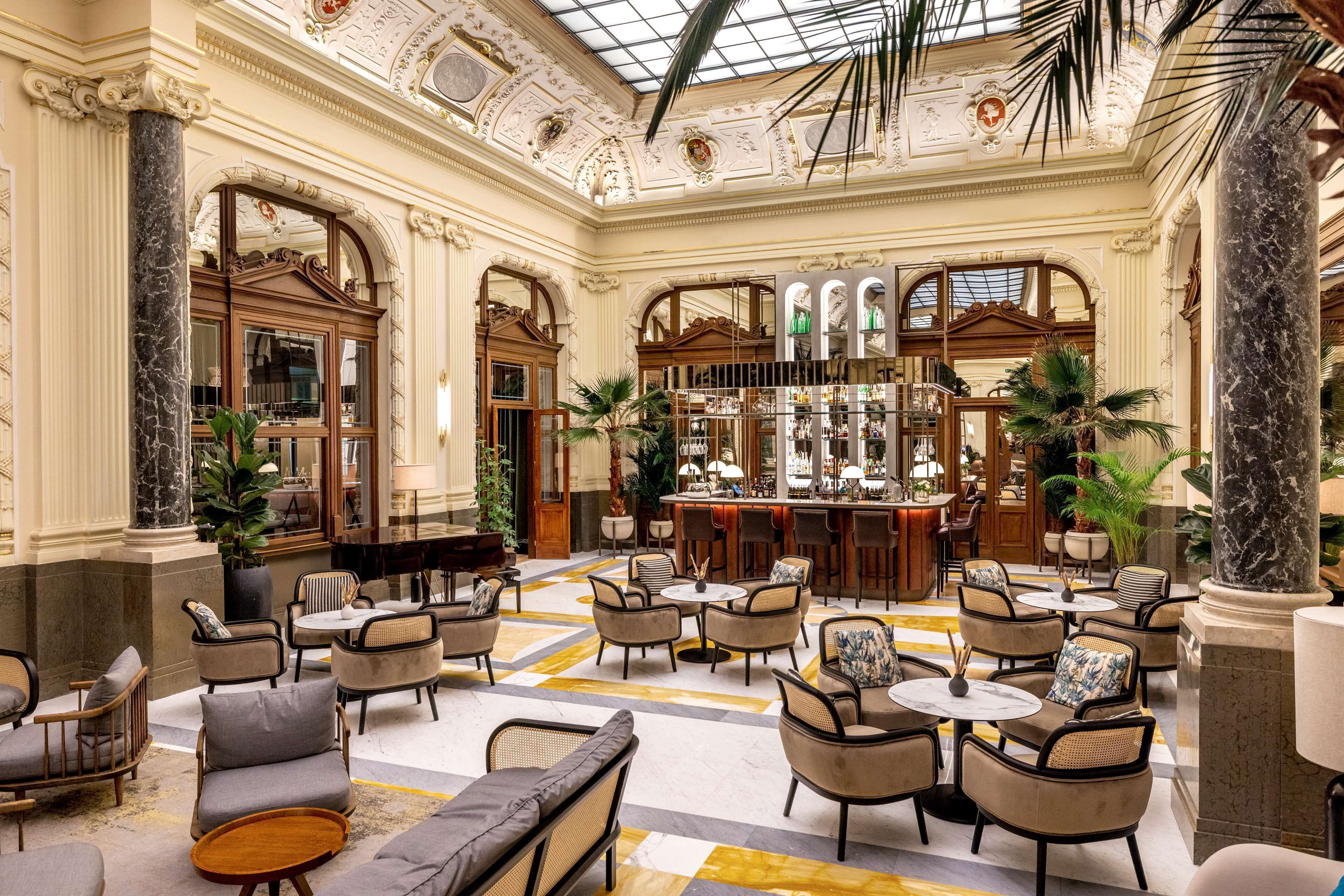 A spacious lobby with a high ceiling, ornate columns, and a central bar area with seating.