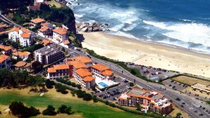 Vue aérienne d’une ville côtière avec ses bâtiments, sa plage et un terrain de golf.