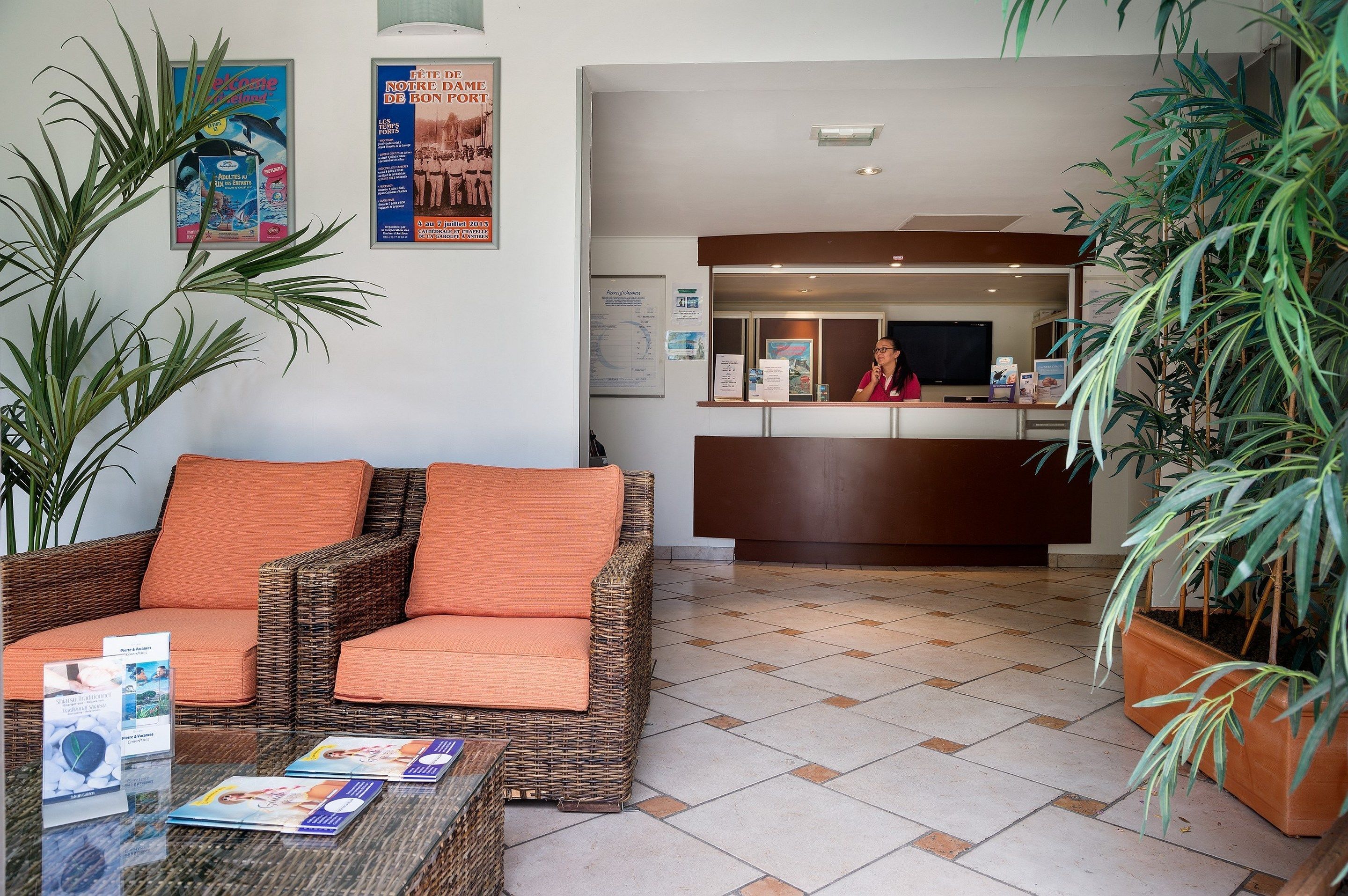 A reception area with a wicker sofa, a glass coffee table with brochures, and a reception desk.