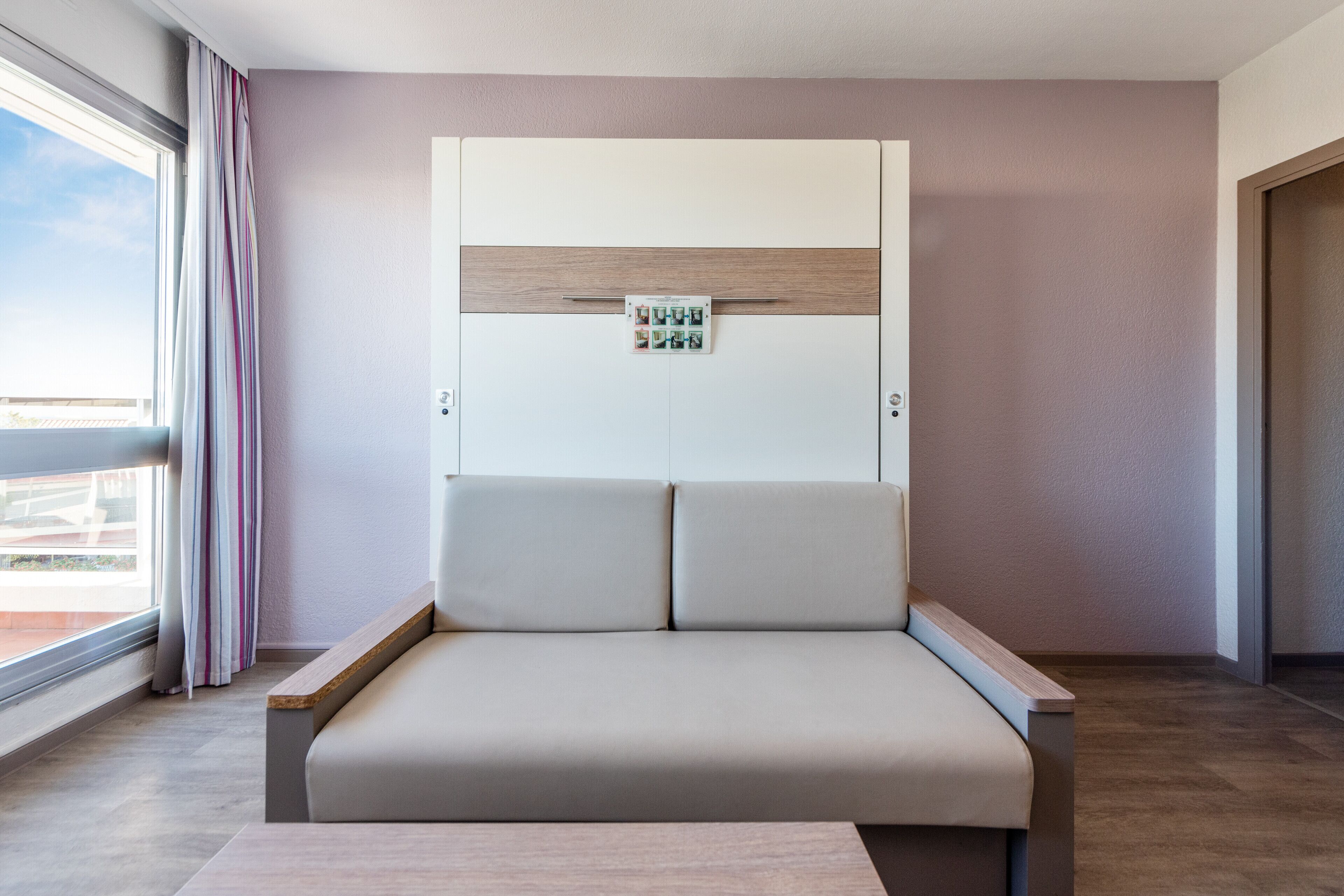 Une chambre moderne avec un canapé-lit, une fenêtre avec des rideaux et une porte.