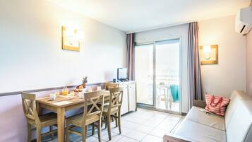 A hotel room with a dining area, a sofa, and a TV.
