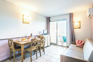 A hotel room with a dining area, a sofa, and a TV. - Pierre & Vacances Résidence La Rostagne (Antibes)