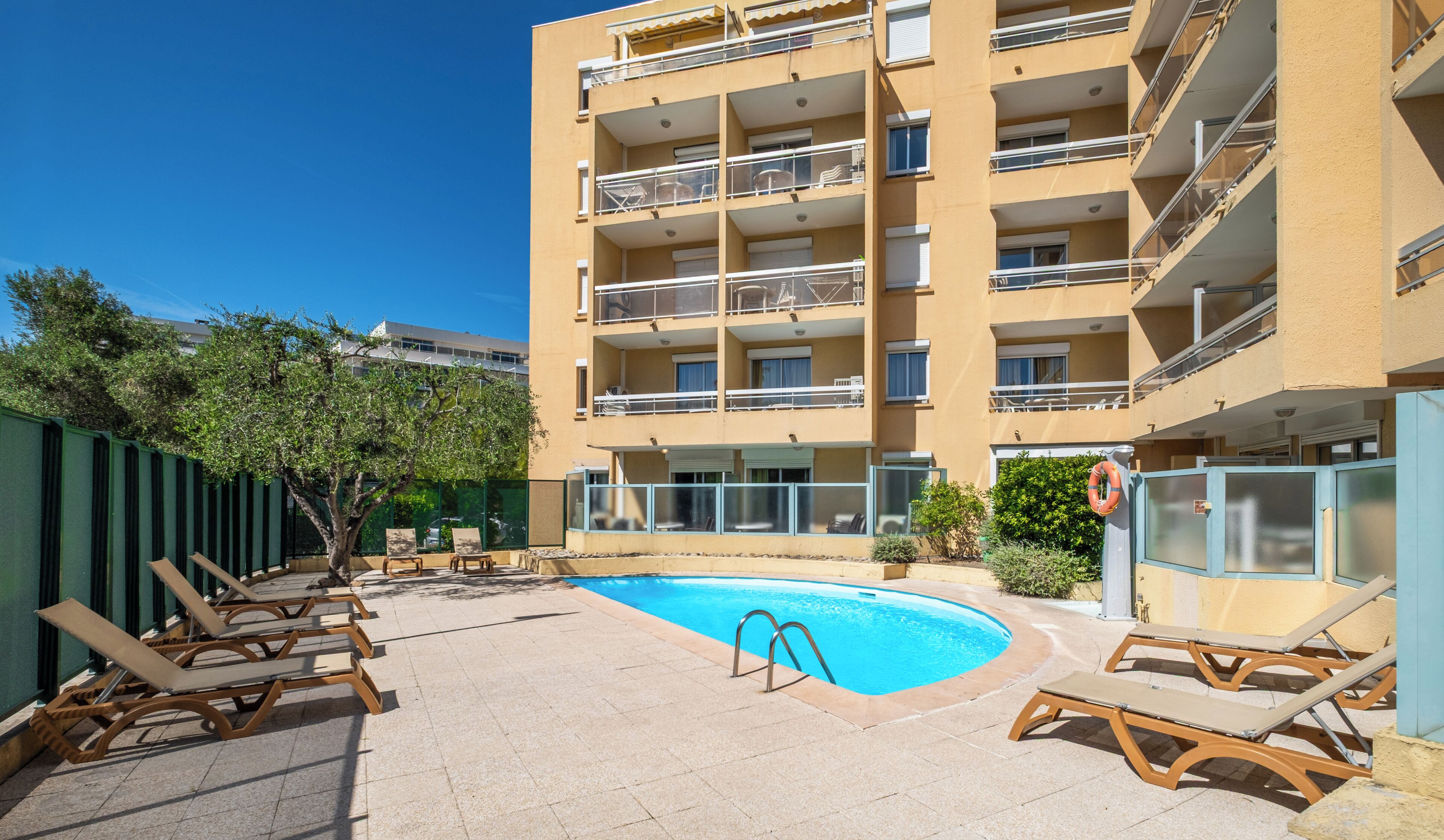 A multi-story building with a swimming pool, outdoor seating, and a lifebuoy.