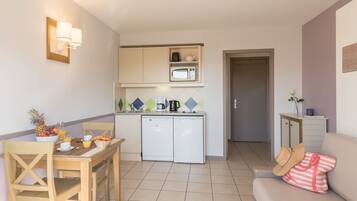 Cocina compacta con microondas, cafetera y refrigerador pequeño.