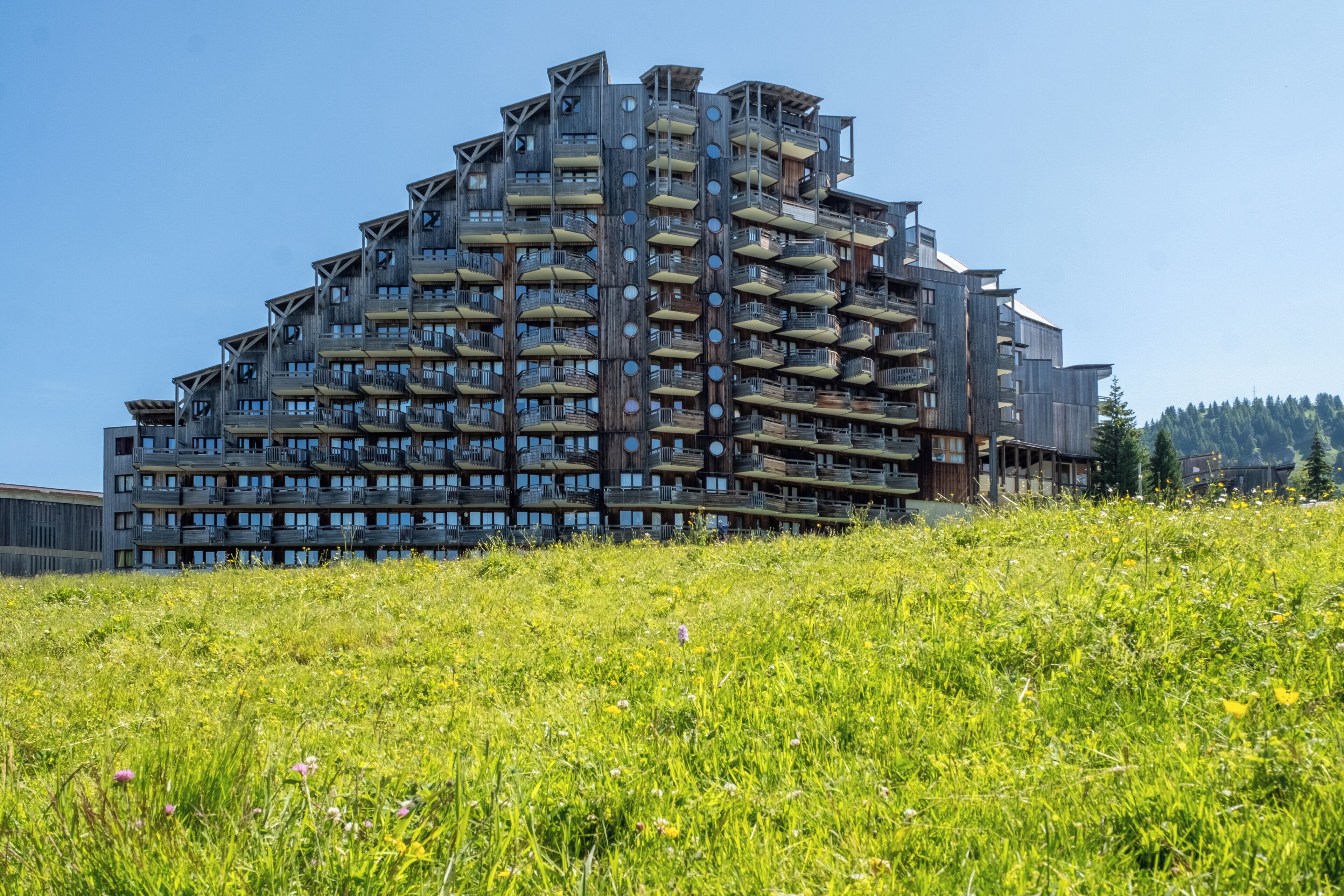 A multi-story building with balconies and a grassy foreground.