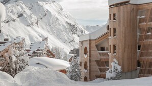 Ein mit Schnee bedeckter Berg mit einem Holzhaus, das Balkone und Fenster hat.
