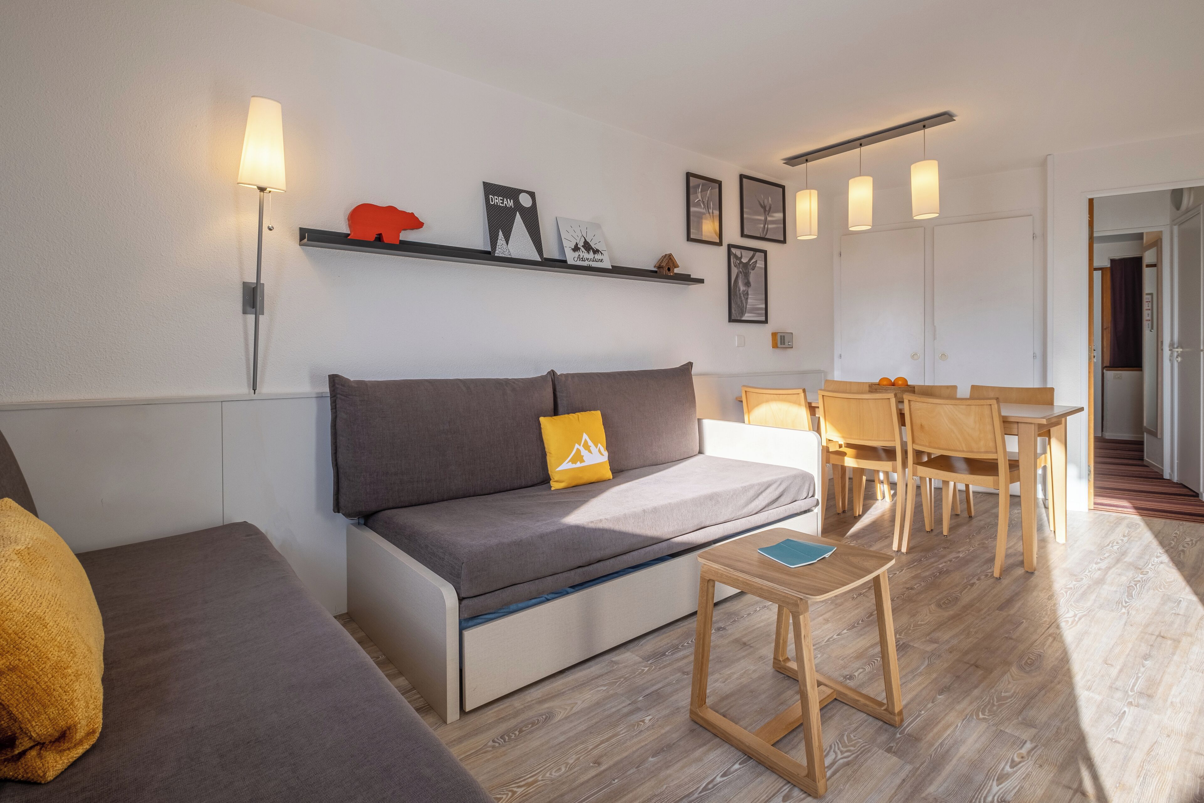 Uma sala de estar moderna com sofá, mesa de centro e área de jantar com cadeiras e mesa.
