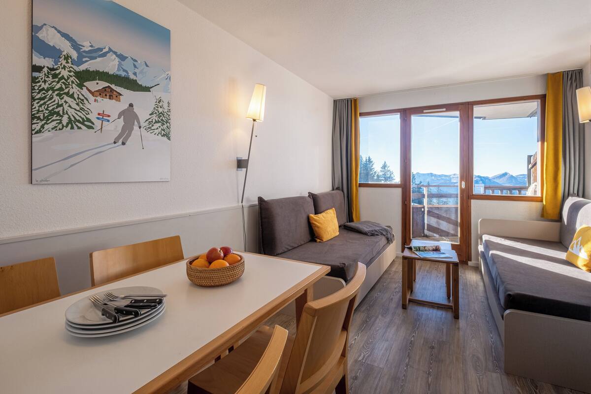 Ein Hotelzimmer mit Essbereich, einer Couch und einem Gemälde eines Skifahrers.