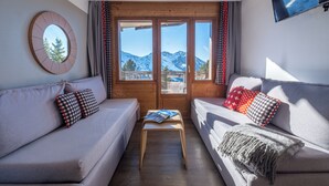 Ein gemütliches Zimmer mit zwei Sofas, einem kleinen Holztisch und Bergblick durch eine Glastür.