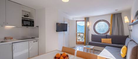 A modern kitchen with a microwave, dishwasher, and a dining area with a table and chairs.