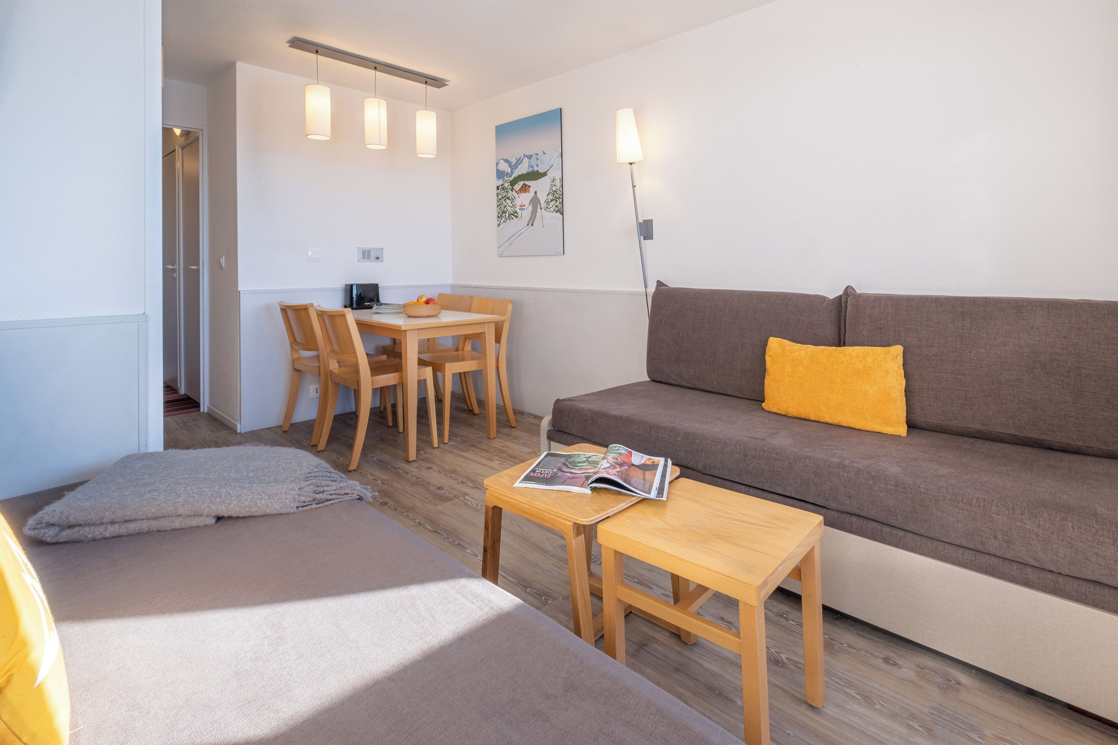 Ein modernes Wohnzimmer mit einer Couch, einem kleinen Tisch, einem Essbereich mit Stühlen und Holzboden.