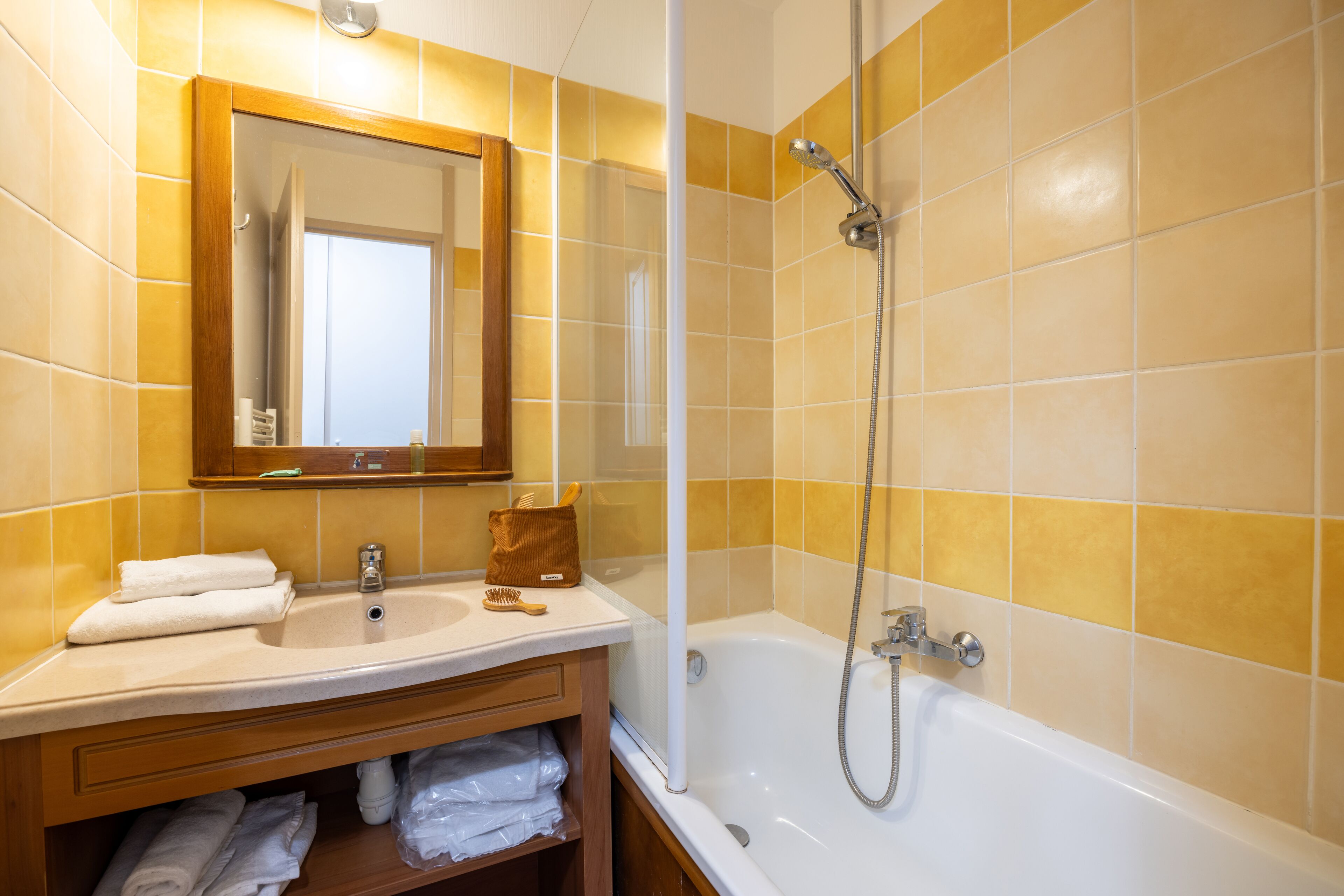 A bathroom with a sink, mirror, and bathtub.