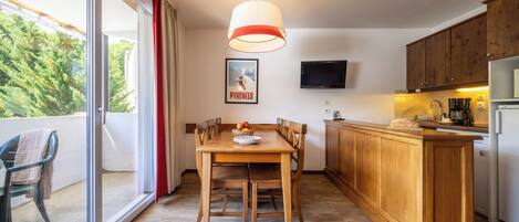 Una cocina moderna con armarios de madera, una mesa de comedor y un amplio ventanal con vistas a árboles.