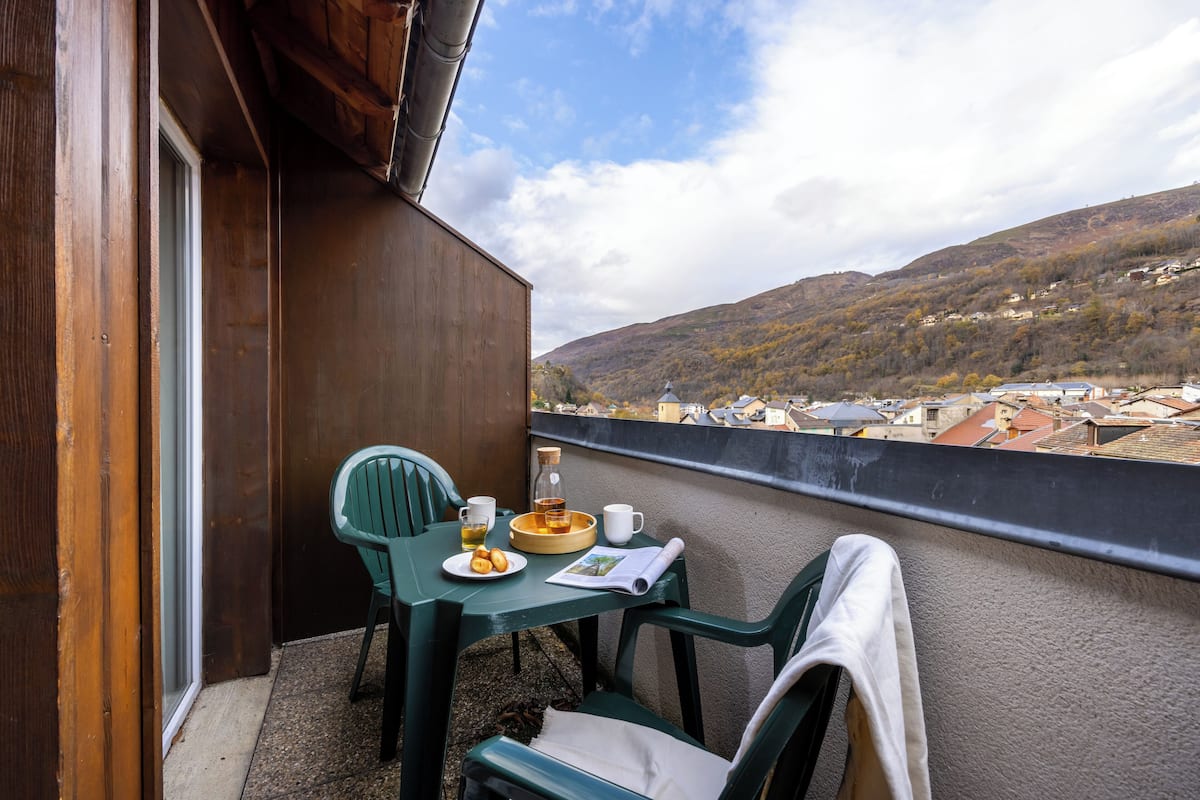 Een balkon met een ontbijttafel, inclusief een bord koekjes, een kopje en een fles sap.
