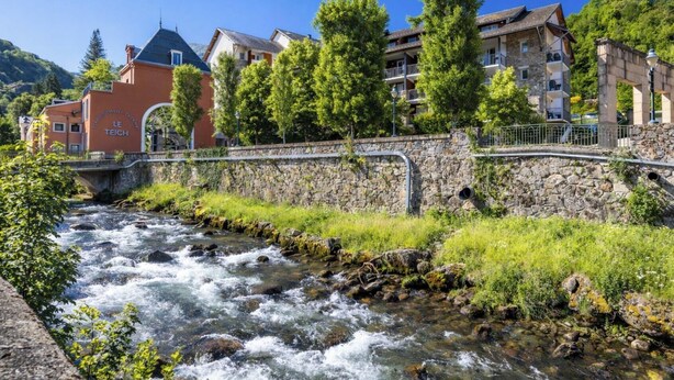 Un río que atraviesa una ciudad con edificios de piedra y un puente.