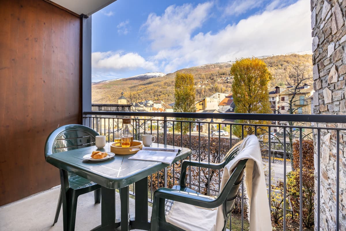 Een balkon met een tafel, stoelen, een fles en een beker.