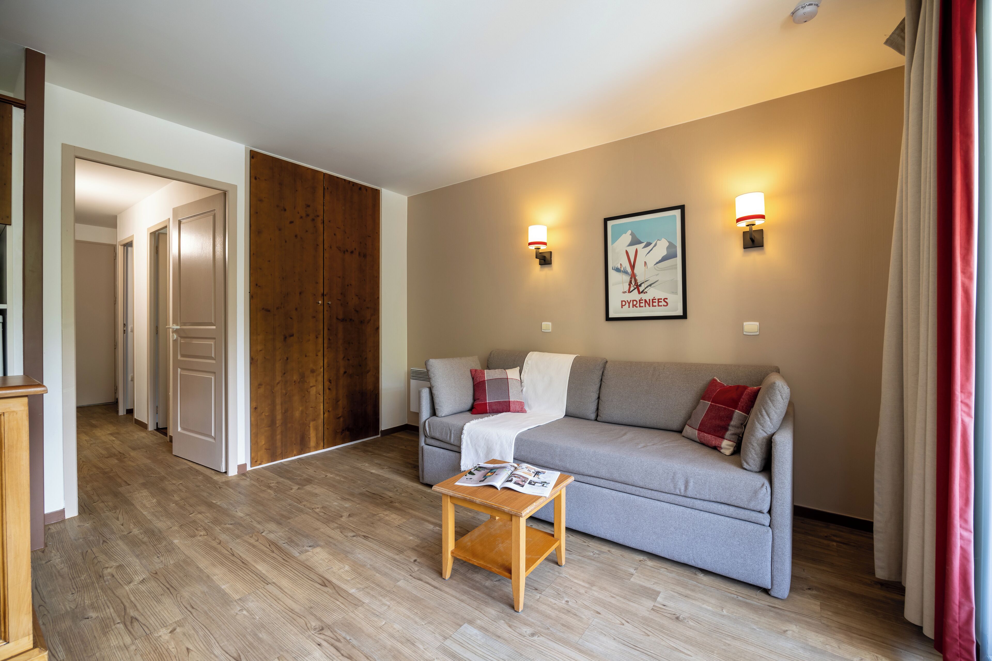 Un salon moderne avec un canapé gris, un plancher en bois et une petite table en bois.