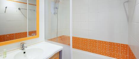 A bathroom with a white sink, mirror, and orange-tiled shower area.