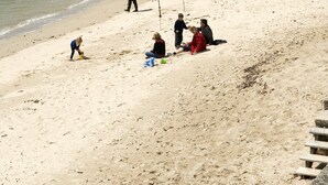 Een strand met mensen die vissen en wandelen langs de kust.