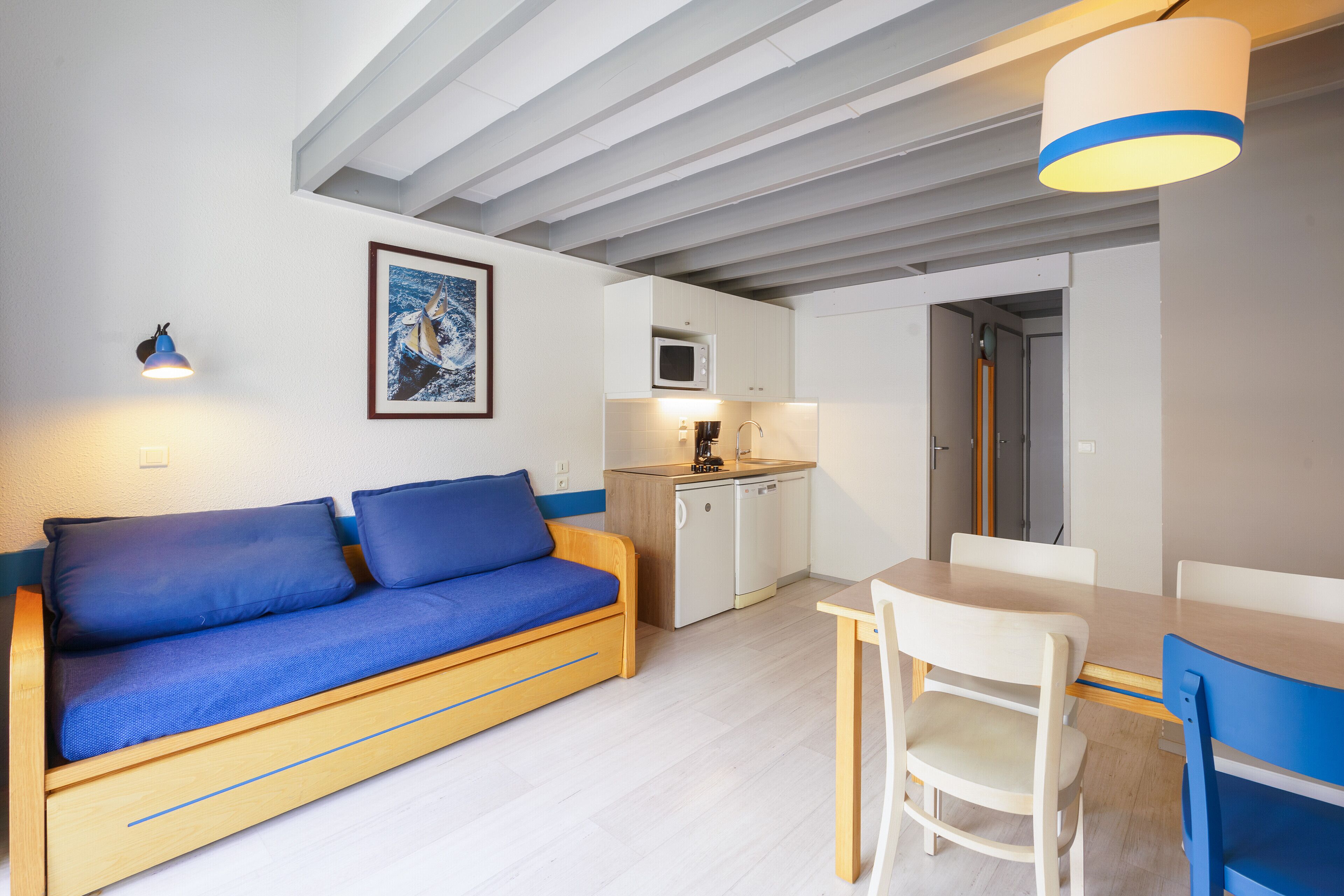 A compact living space with a sofa, a dining table, and a kitchenette.