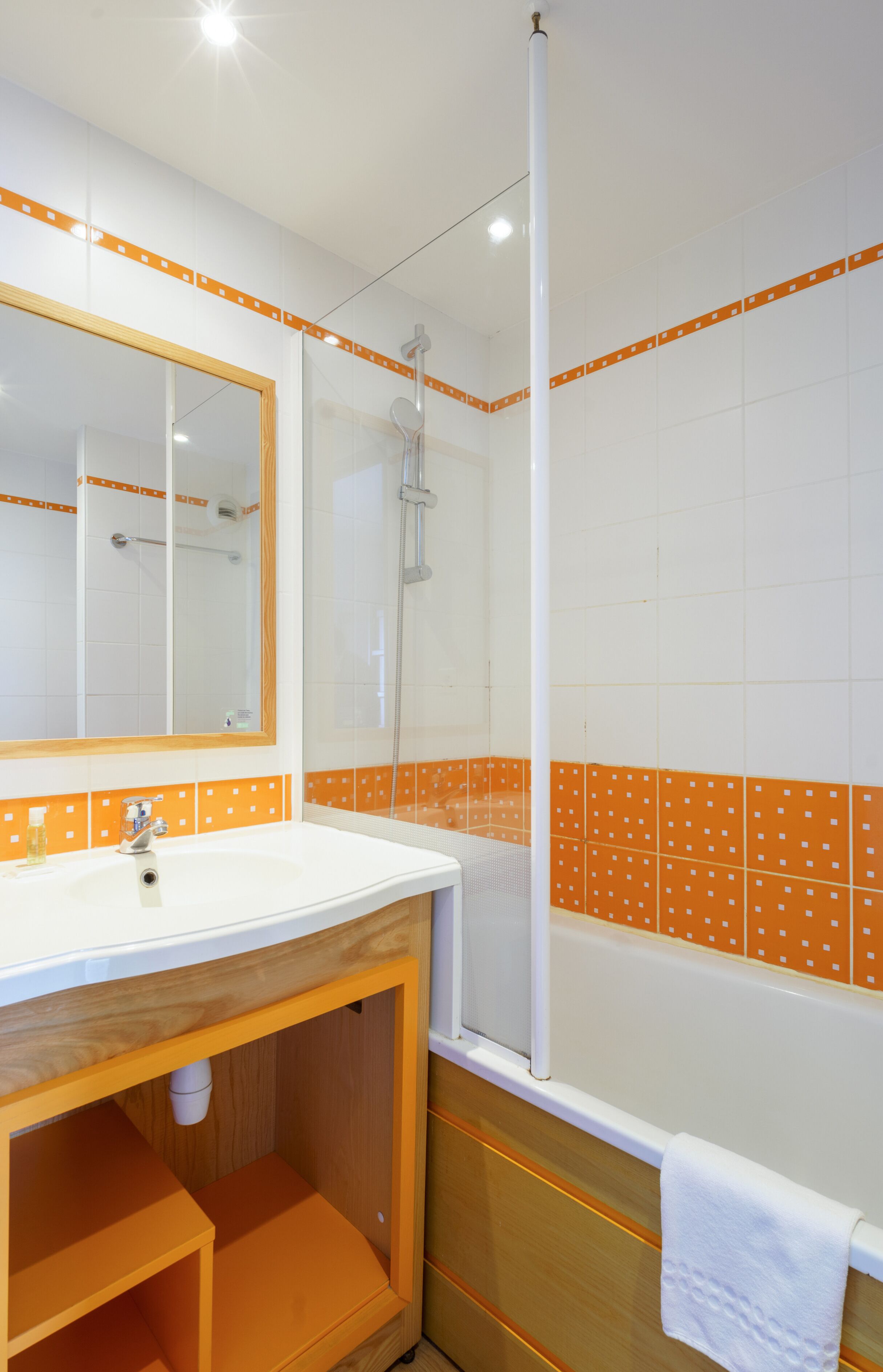 A bathroom with a white sink, wooden vanity, and orange-tiled walls.