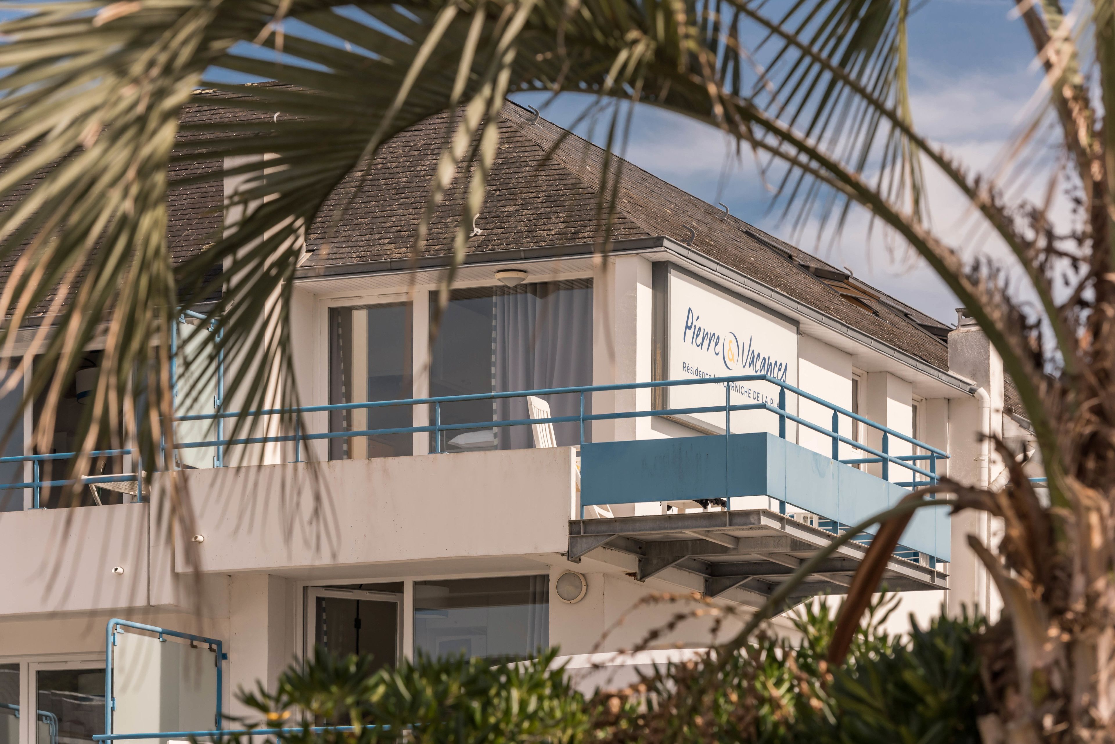 A two-story building with a balcony, a sign reading "Pierre Jacque," and a palm tree in the foreground.