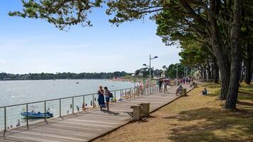 A wooden boardwalk along a waterfront with people walking and sitting.