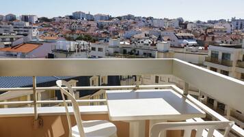 Un balcon avec une table et des chaises, donnant sur un quartier résidentiel densément peuplé, composé de différents types d’immeubles.