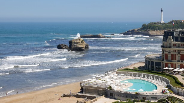 A coastal hotel with a pool, ocean views, and a lighthouse in the background. - Résidence Victoria Surf (Biarritz)