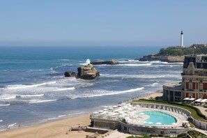 A coastal hotel with a pool, ocean views, and a lighthouse in the background. - Résidence Victoria Surf (Biarritz)