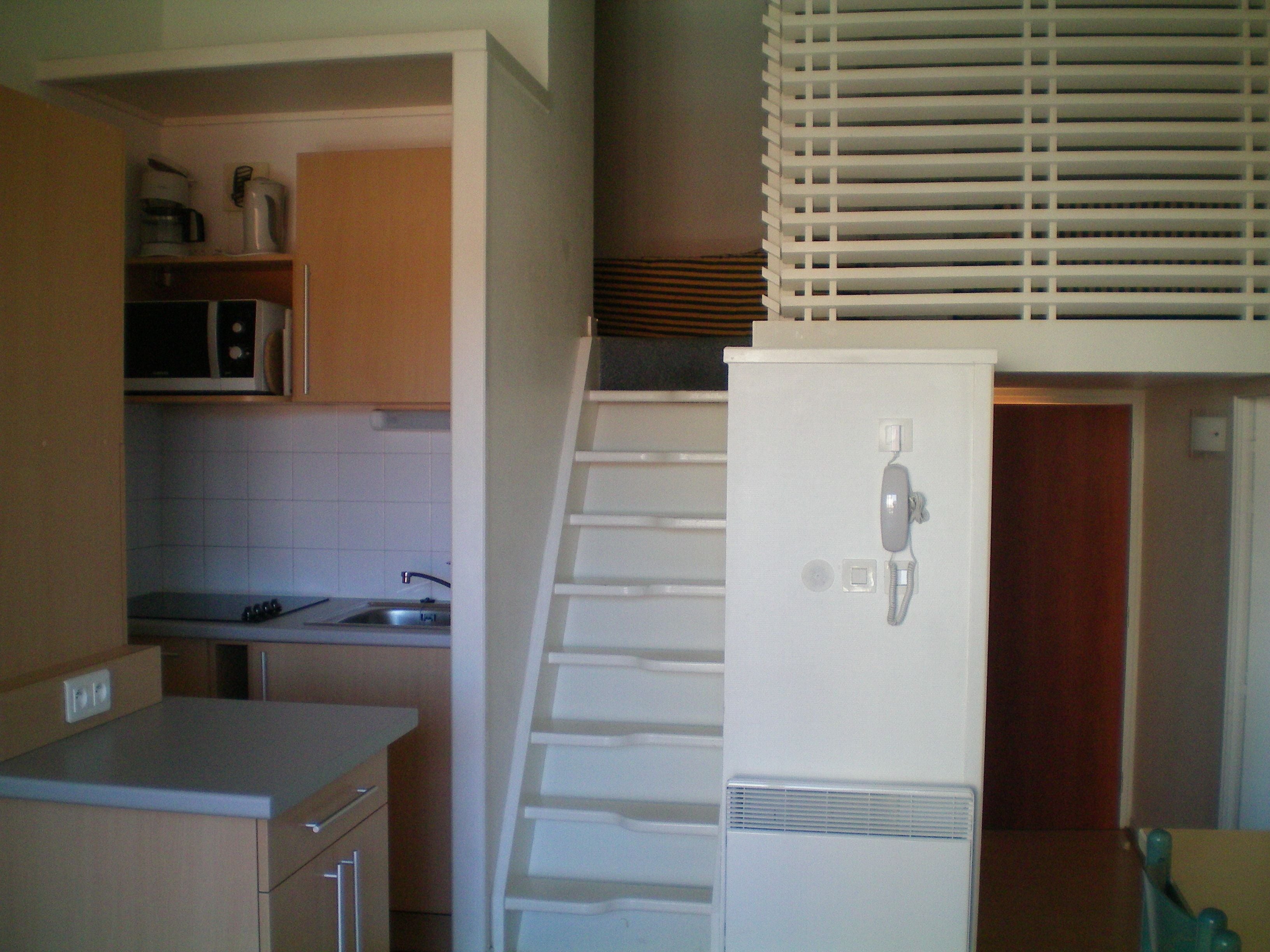 A compact kitchen with a microwave, sink, and white refrigerator.