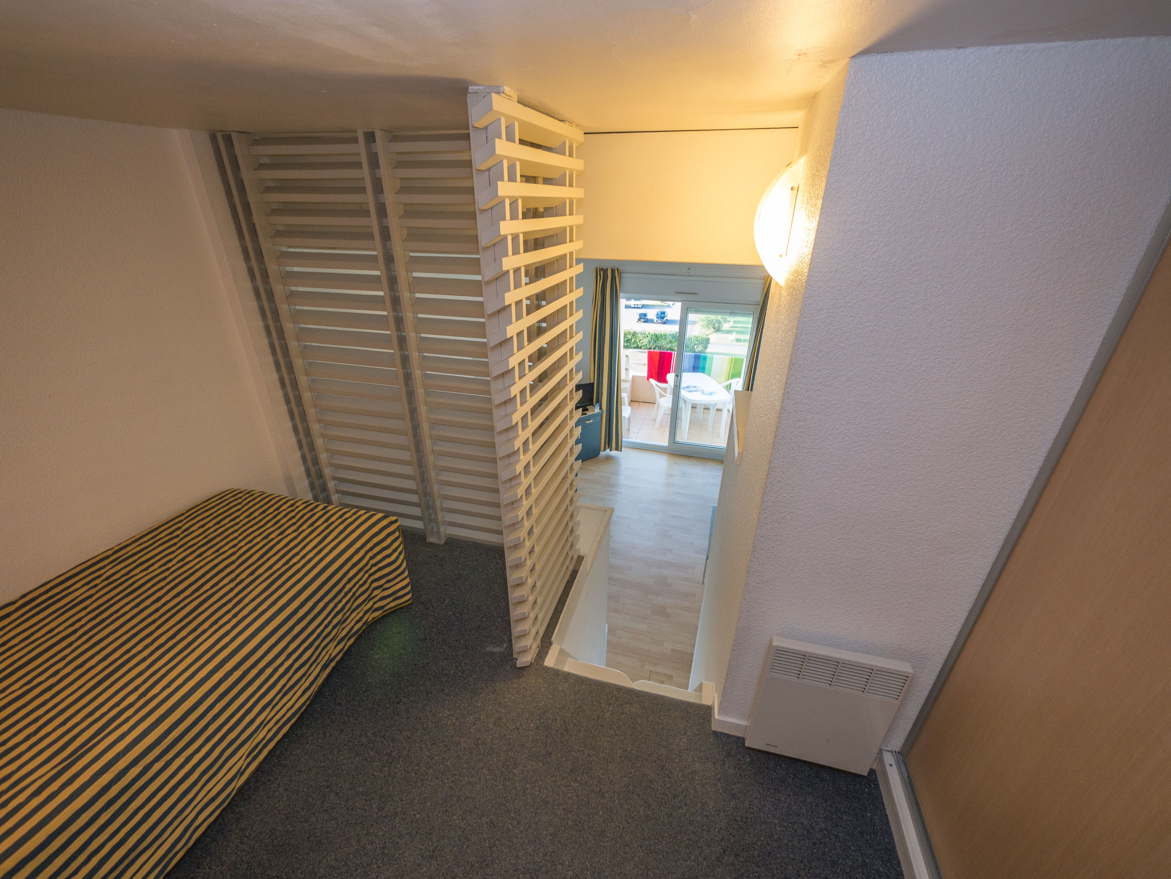 A narrow hallway with a striped bench, a sliding door, and a radiator.