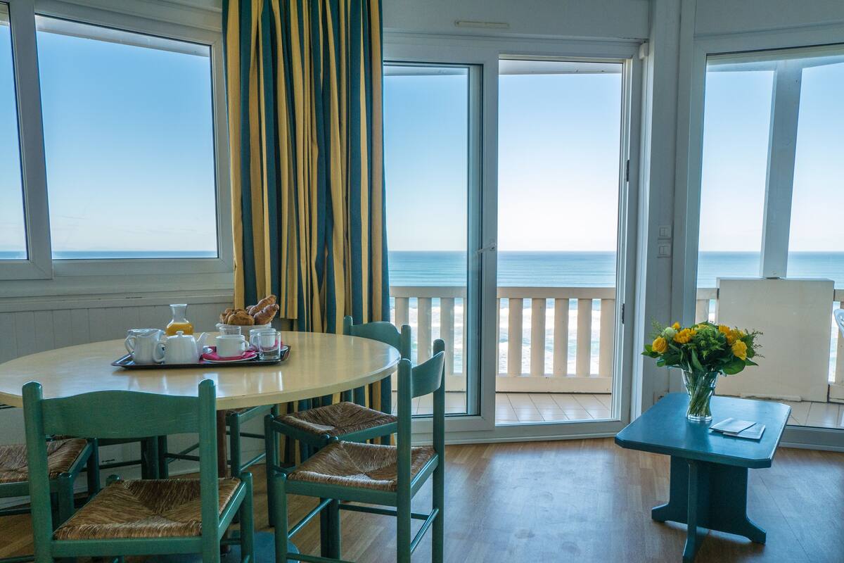 A dining area with a table, chairs, and a view of the ocean.