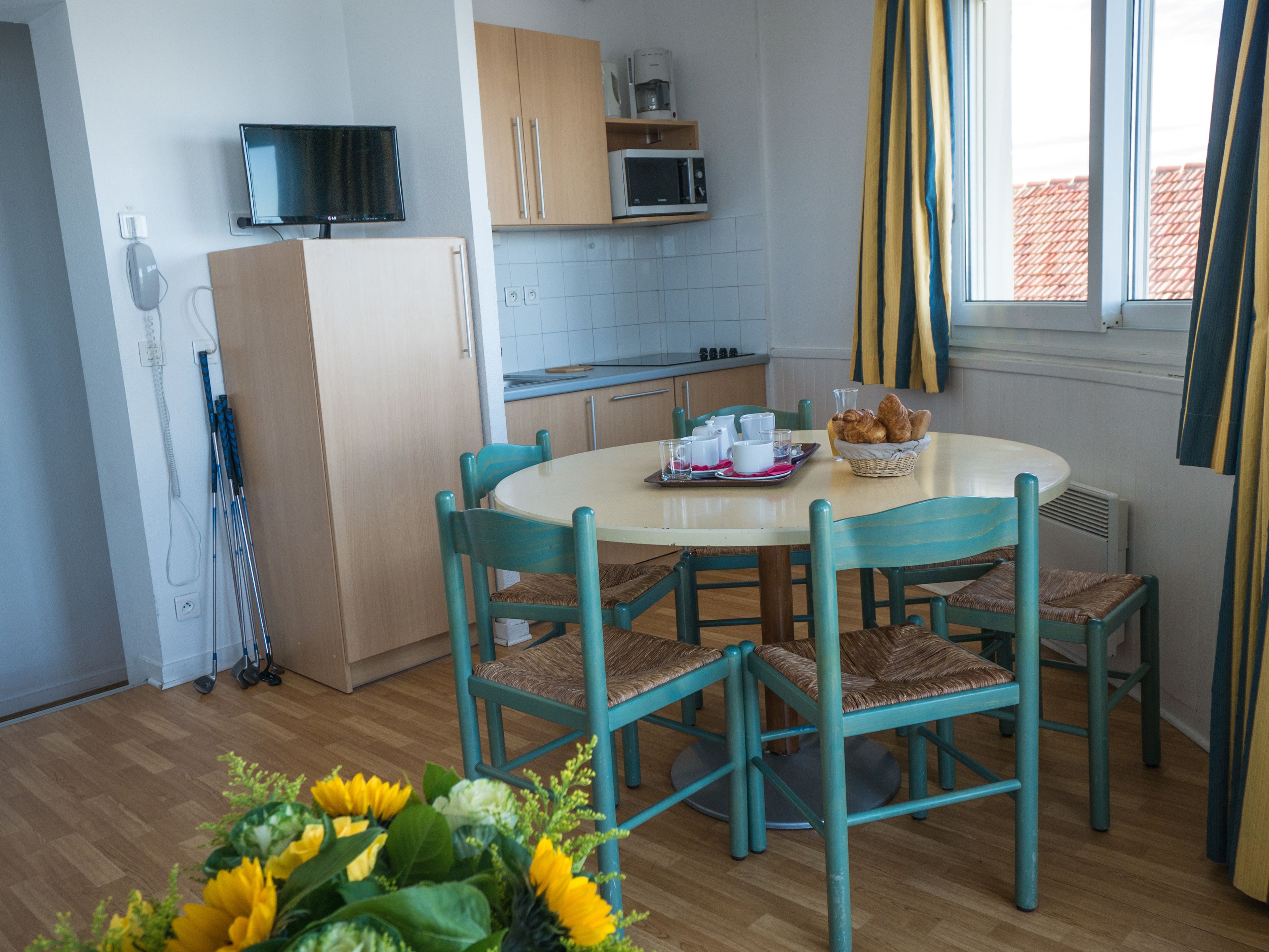 A dining area with a round table, four chairs, and a breakfast setting including croissants and coffee.