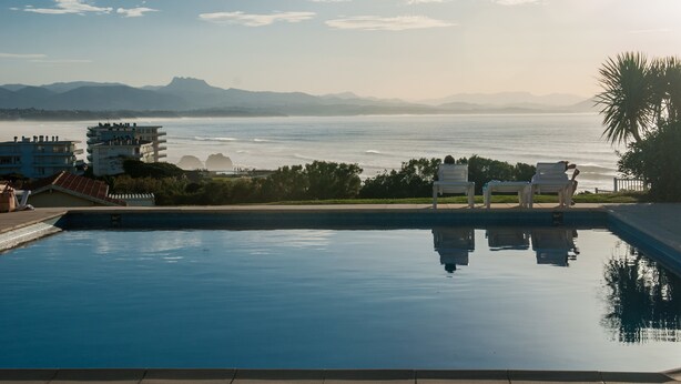 A swimming pool with a view of the sea and mountains in the background. - Résidence Eugénie (Biarritz)