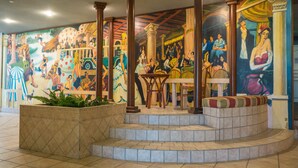 A lobby with a colorful mural, a seating area with a small table, and a planter with greenery. - Résidence Eugénie (Biarritz)