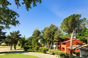A residential area with a red building, surrounded by trees and greenery. - SOWELL HÔTELS L'Olivier (Arles)