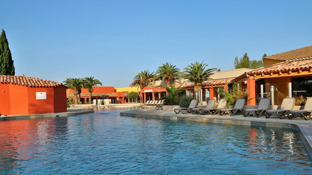 Una piscina con sillones de descanso y palmeras.