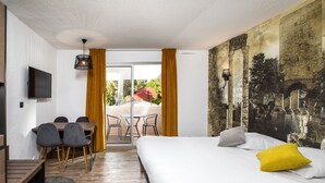 Una habitación de hotel con una cama, un escritorio con sillas, un televisor y un mural en la pared.