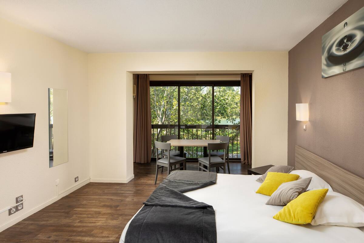 Ein Hotelzimmer mit Bett, Fernseher, Tisch und Stühlen.