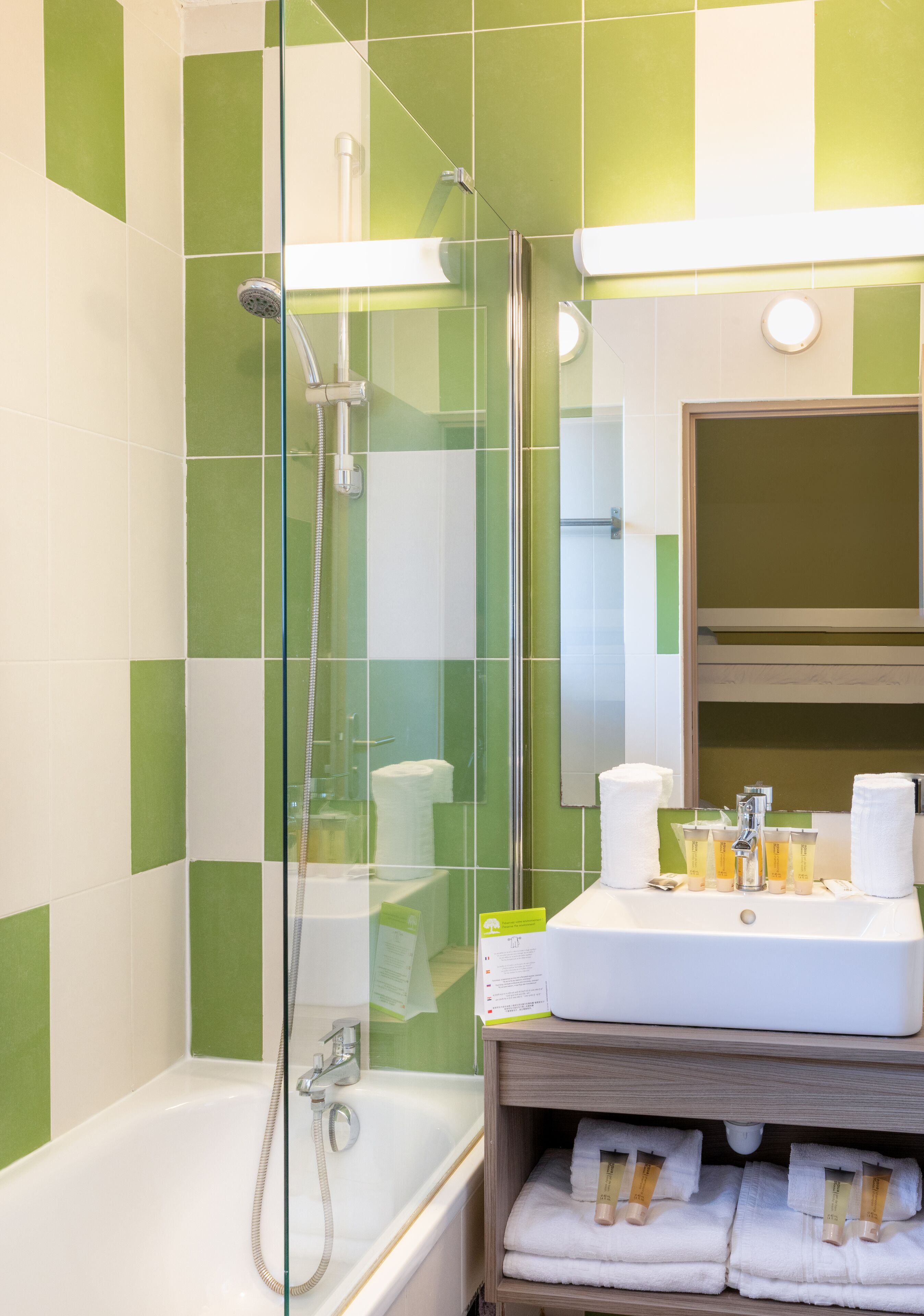 Un baño con cabina de ducha de vidrio, una bañera blanca y un tocador con toallas y artículos de aseo.