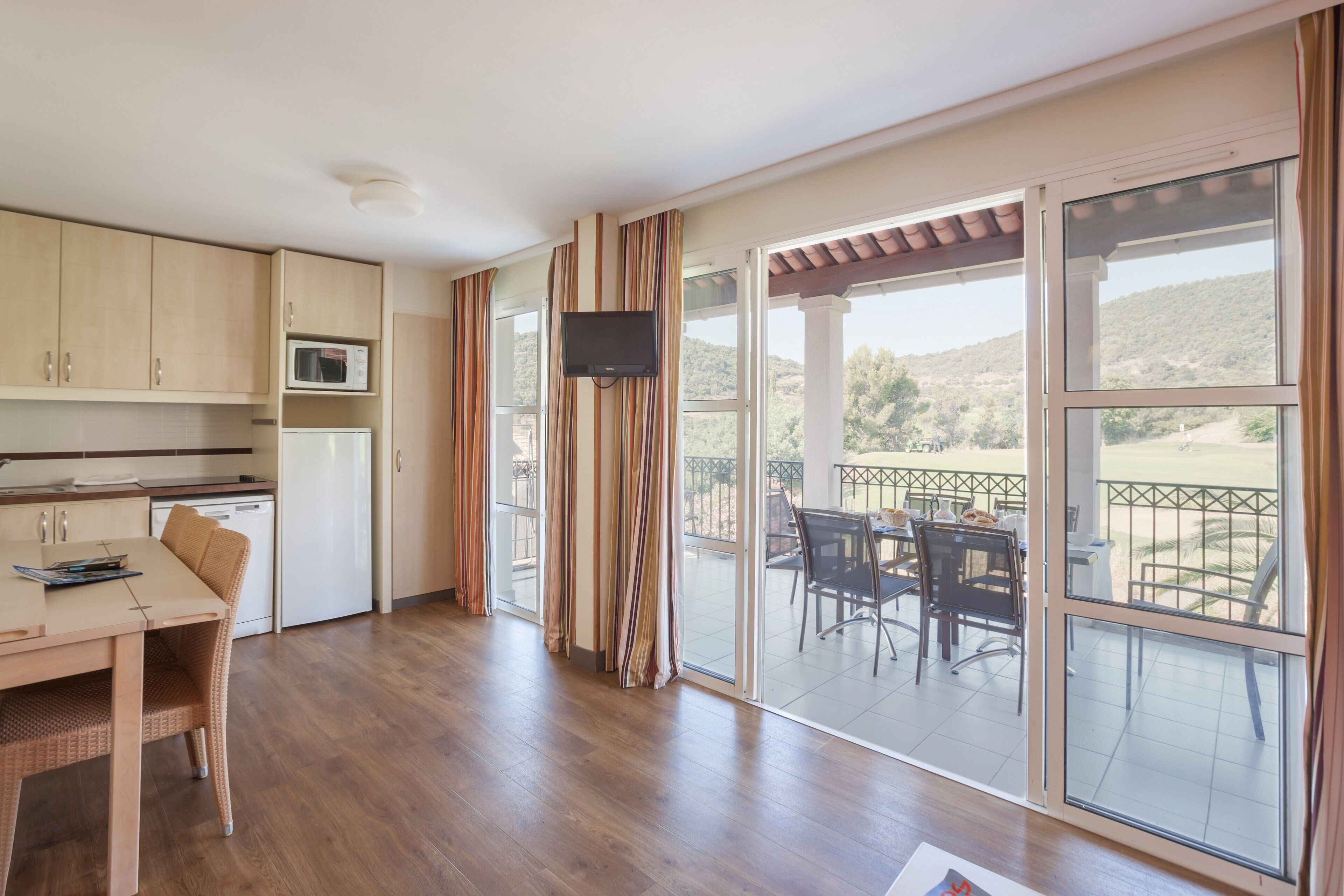 A spacious kitchen with wooden cabinets, a microwave, and a dining area with a table and chairs.