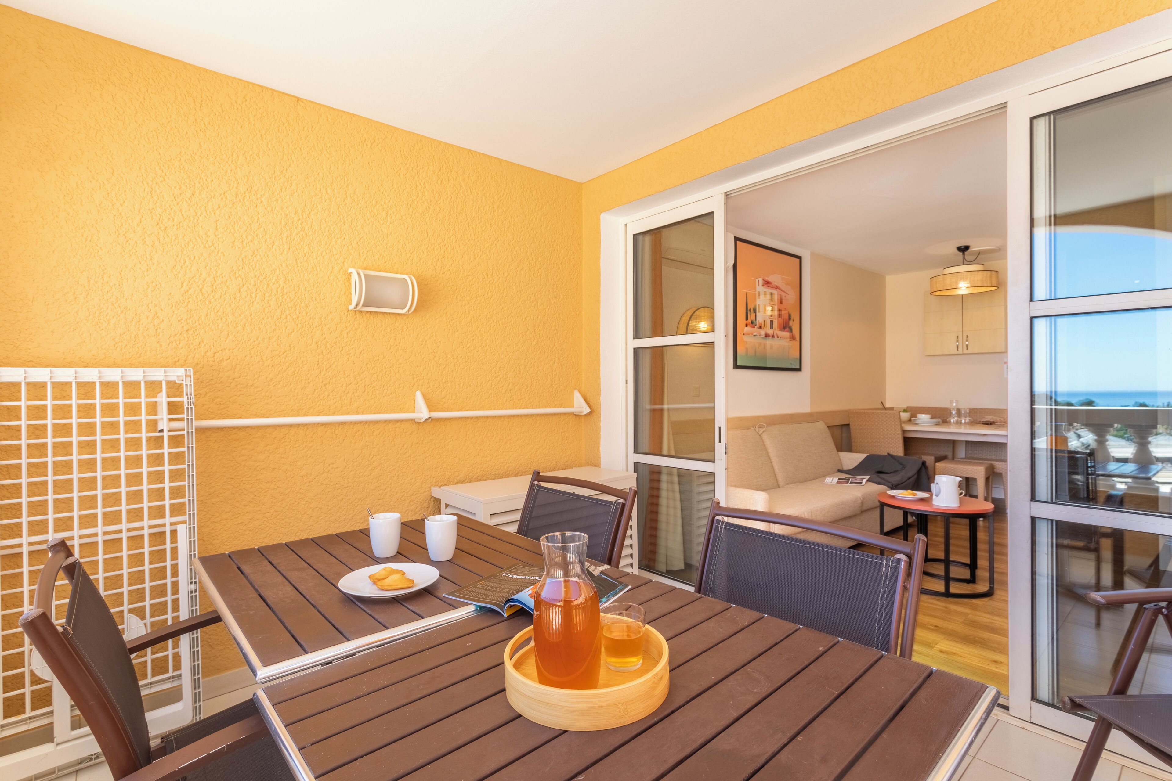 Un comedor con una mesa de madera, sillas y un centro de mesa de vidrio. Hay una ventana con vistas al exterior.