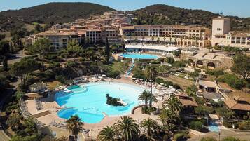 A resort with multiple swimming pools, a central courtyard, and a mountainous backdrop.