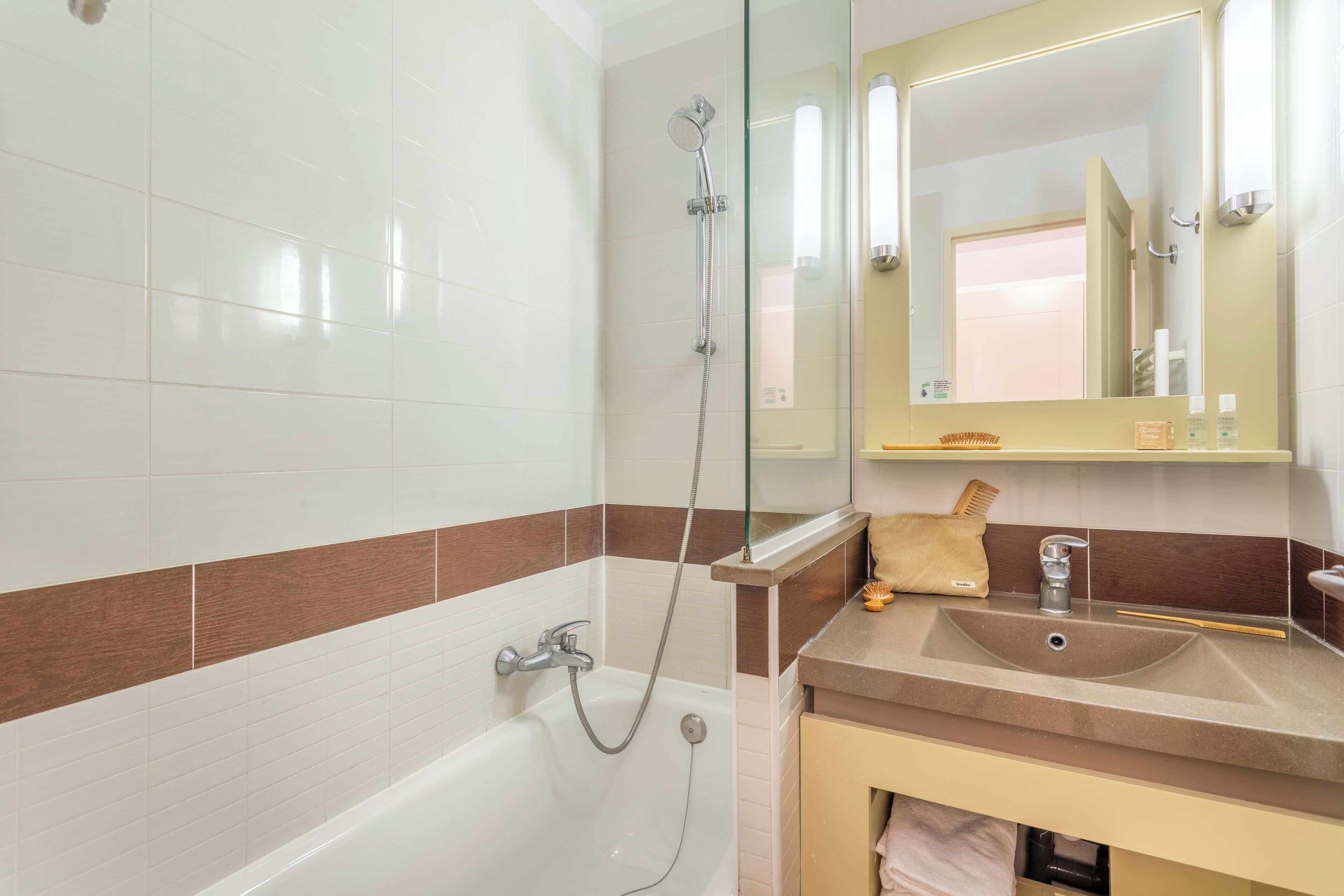 Une salle de bain équipée d’une baignoire, d’un lavabo, d’un miroir et d’un porte-serviettes.
